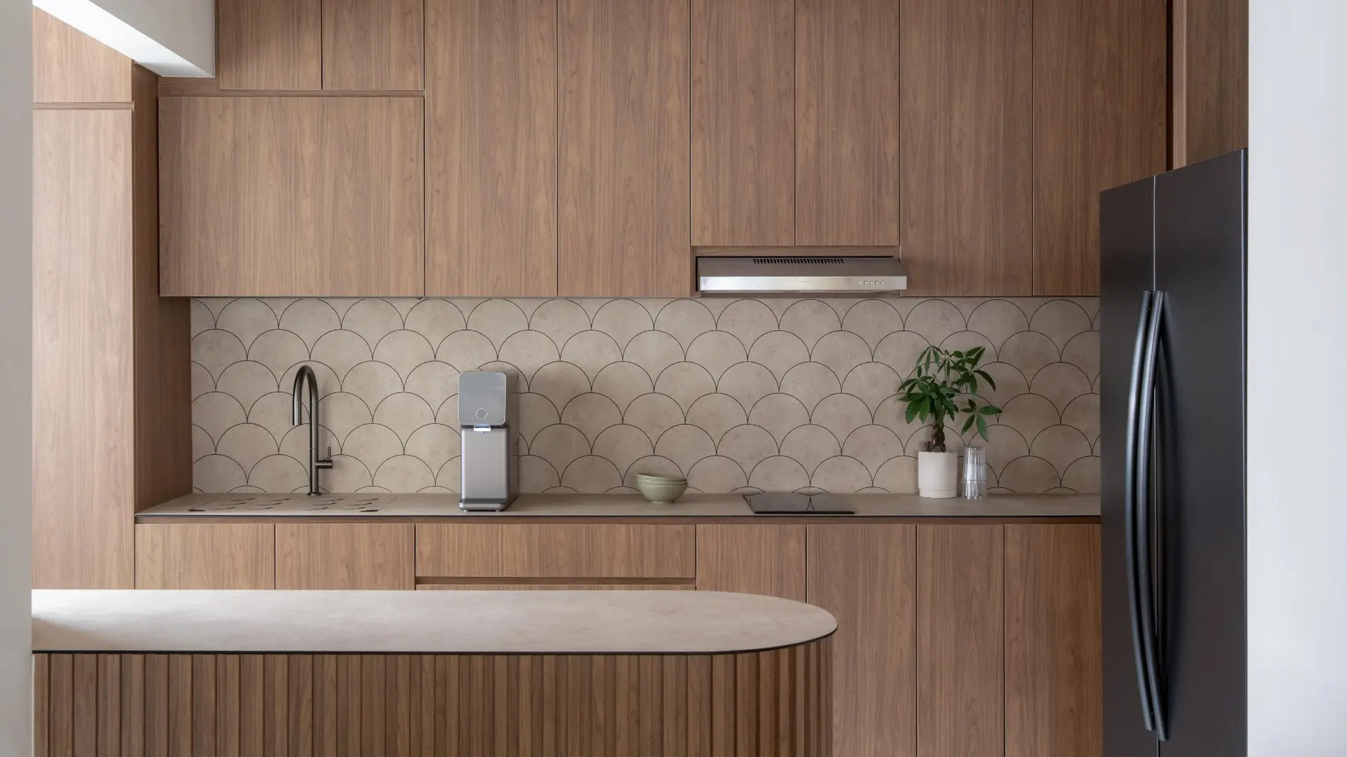 Warm timber kitchen cabinetry with scallop-tile backsplash and fluted island by 6AM Spaces Singapore